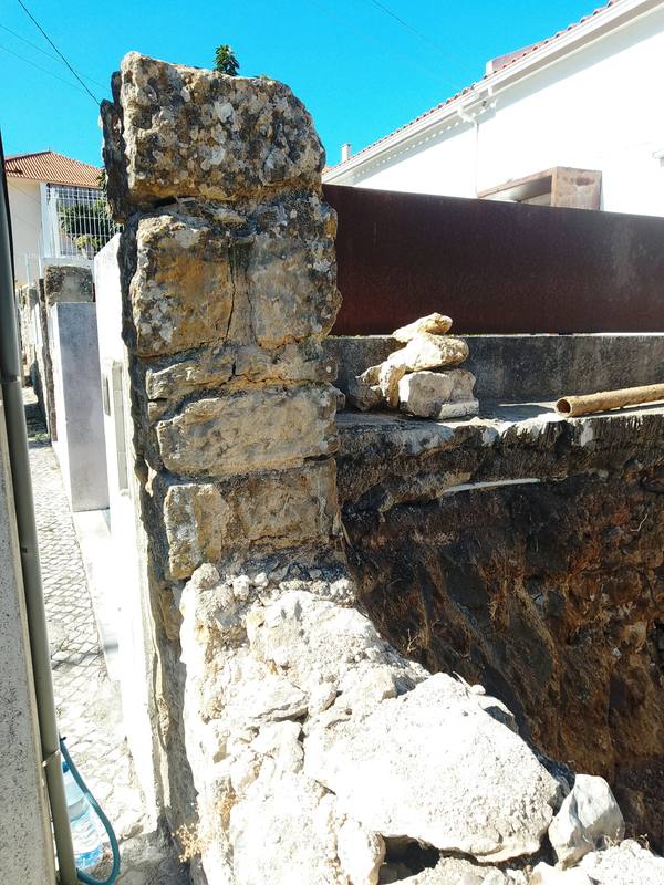 Muro antigo de alvenaria de pedra posto à vista pela escavação